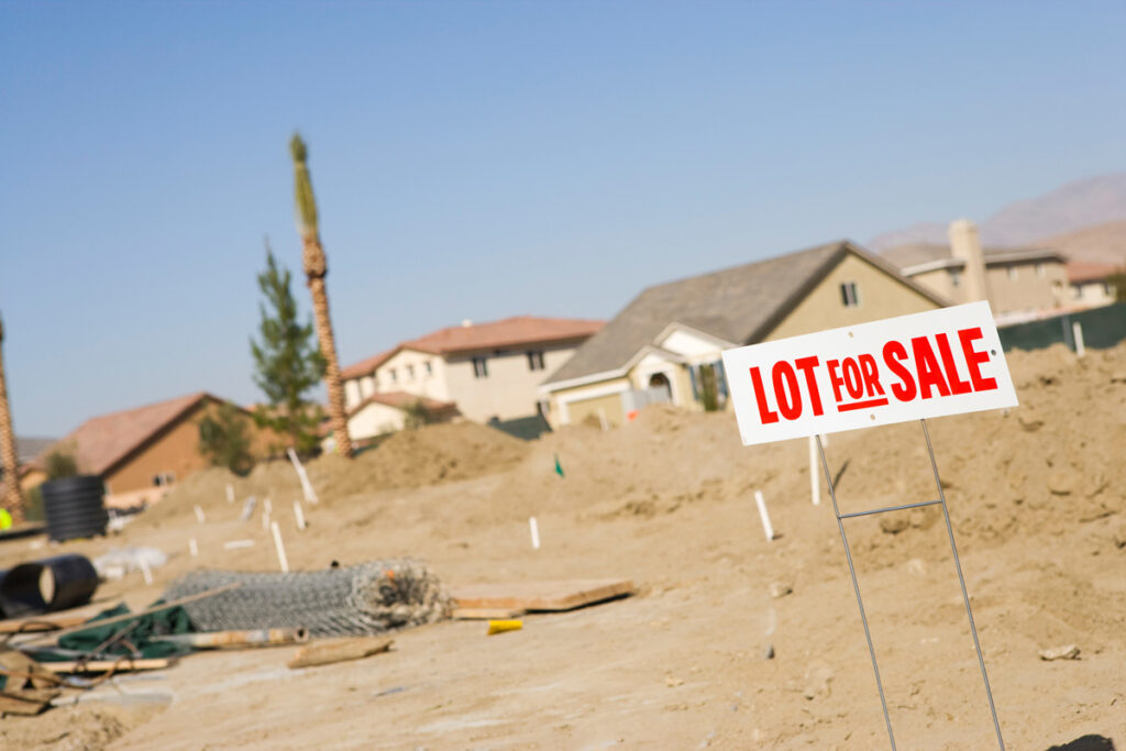 A dirt lot with a white and red sign that reads “LOT FOR SALE” in El Paso