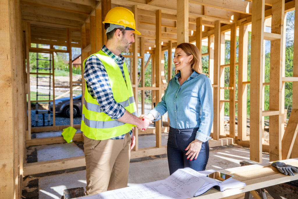 A home builder and woman shaking hands in the frame of a new luxury home in El Paso.